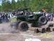 1989 Ford Bronco - Spectators watch as a modified off-road vehicle navigates a log obstacle course.