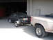 1989 Ford Taurus - A black sedan is being towed by a pickup truck inside a garage.