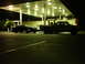 1989 Ford Taurus - Two vehicles are parked at a gas station at night under the illuminated canopy.