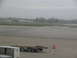 1995 Ford C-350 (Centurion Conversions) - Cargo containers and a tow tractor sit on an airport tarmac during overcast weather.