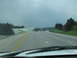 1995 Ford C-350 (Centurion Conversions) - View from a car driving on a highway with other vehicles under a cloudy sky.
