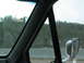 1995 Ford C-350 (Centurion Conversions) - View from inside a vehicle, looking out the side window and mirror at a wooded hillside.