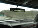 1995 Ford C-350 (Centurion Conversions) - View from inside a vehicle traveling on a highway, with trees and a body of water visible alongside the road.