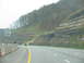 1995 Ford C-350 (Centurion Conversions) - Driving on a highway with a speed limit sign and a view of layered rock formations on a hillside.