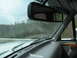 1995 Ford C-350 (Centurion Conversions) - Driving through a wooded area with a cloudy sky overhead.