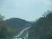 1995 Ford C-350 (Centurion Conversions) - Traffic moves along a highway surrounded by trees and hills under a cloudy sky.