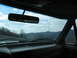 1995 Ford C-350 (Centurion Conversions) - View from inside a vehicle, showing the dashboard and windshield with a backdrop of rolling hills and a cloudy sky.