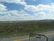 1995 Ford C-350 (Centurion Conversions) - View from a vehicle traveling on a highway under a cloudy blue sky.