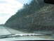1995 Ford C-350 (Centurion Conversions) - A view of a rocky cliff face with icicles hanging down, seen from the perspective of a vehicle driving on a road.