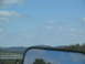 1995 Ford C-350 (Centurion Conversions) - Reflection in the side mirror shows trees and the sky on a cloudy day.