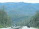 1995 Ford C-350 (Centurion Conversions) - A highway passes through a valley with tree-covered mountains under a hazy sky.