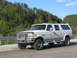 1995 Ford C-350 (Centurion Conversions) - Silver four-door SUV with a custom conversion, parked on a road with trees in the background.