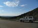 1995 Ford C-350 (Centurion Conversions) - A white extended cab pickup truck with a camper shell is parked on the side of a road overlooking a valley.