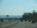 1995 Ford C-350 (Centurion Conversions) - Traffic moves along a multi-lane highway with overhead signs and trees lining the roadside.