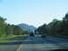 1995 Ford C-350 (Centurion Conversions) - Driving on a highway with mountains in the background and other vehicles on the road.