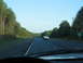1995 Ford C-350 (Centurion Conversions) - Driving on a highway with a white convertible ahead and trees lining the road.