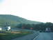1995 Ford C-350 (Centurion Conversions) - Multiple vehicles travel on a highway with a large hill in the background and construction signs.
