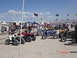 1981 Ford Bronco - A collection of ATVs are parked in a sandy area, with a crowd and various vehicles in the background.