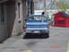 1981 Ford Bronco - A blue Chevrolet pickup truck is seen from the rear, parked next to a red dumpster.