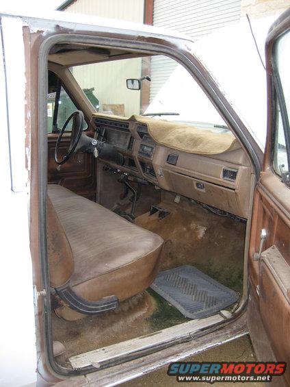 Interior view of a brown bench seat and dashboard of an older Ford truck