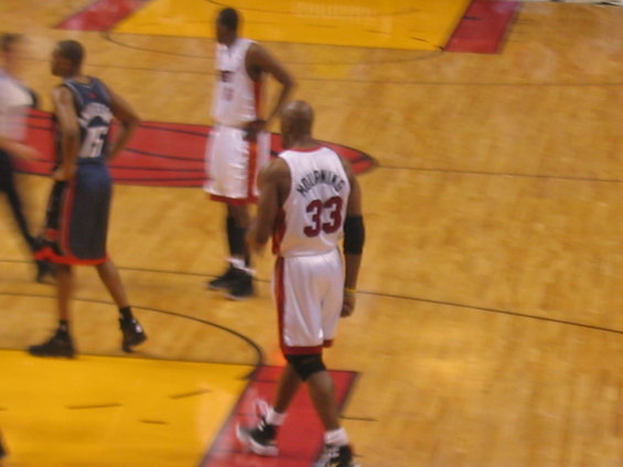 Basketball players in white and blue uniforms on a wooden court