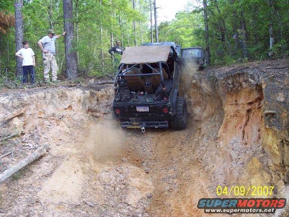 Off-road vehicle descending steep dirt embankment, kicking up dust