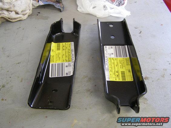 Two black metal automotive parts with yellow labels and barcodes
