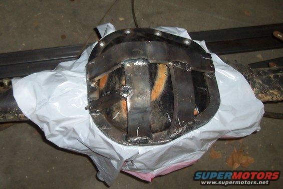 Differential cover with welded metal reinforcement plates, partially covered by white plastic