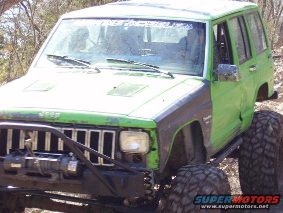 Green Jeep Cherokee XJ with off-road tires and a winch on the front bumper