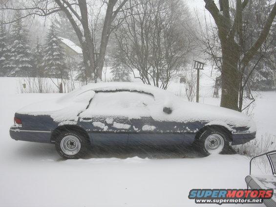 Side view of a blue 1996 Ford Crown Victoria covered in snow