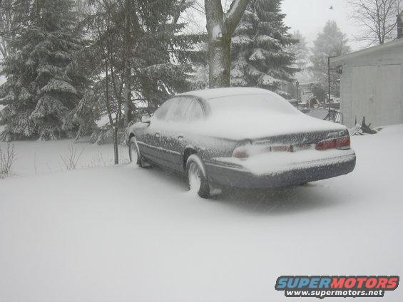 Rear view of a 1996 Ford Crown Victoria parked in heavy snow