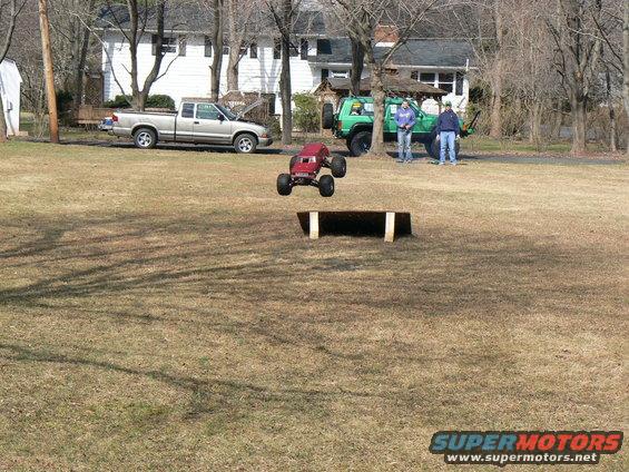 Red RC monster truck mid-air over ramp