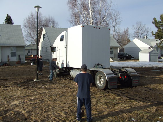 Semi-trailer truck with a white box trailer, viewed from the rear, on muddy ground