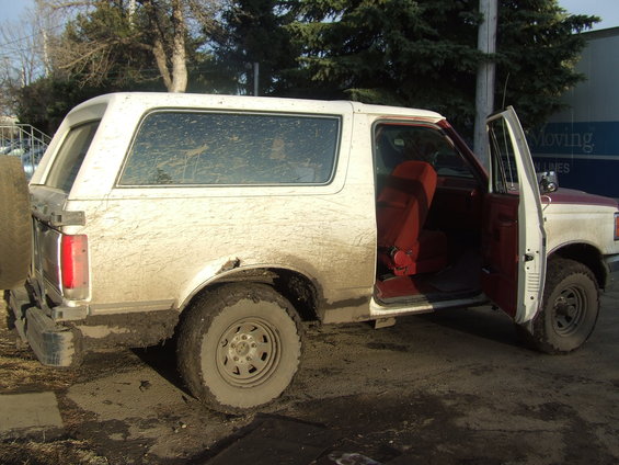 1990 Ford Bronco side view, white and red, mud-covered, red interior, doors open