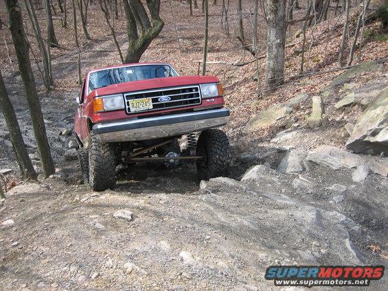 Red 1990 Ford Bronco 4x4 navigating a rocky trail