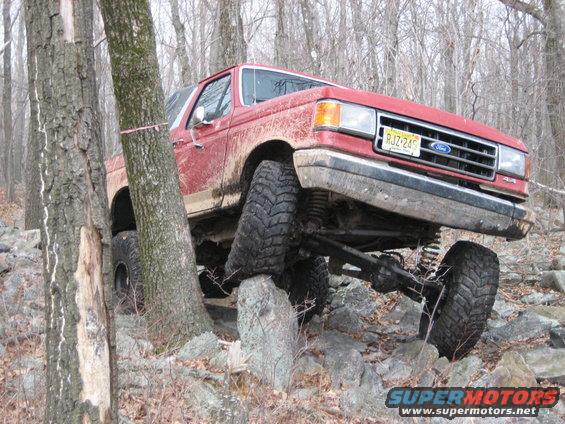 1990 Ford Bronco with lifted suspension navigating rocky terrain