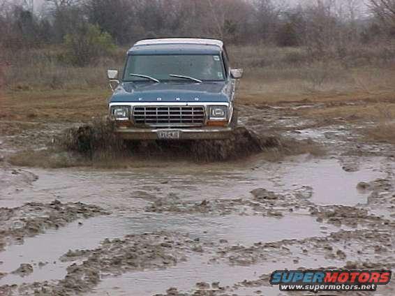 1978 Ford Bronco driving through a muddy field