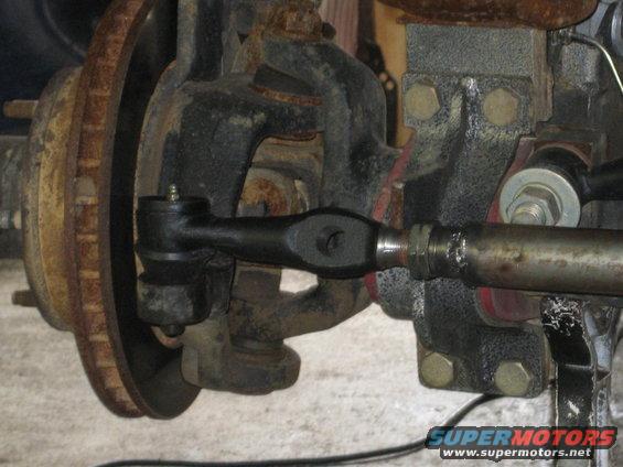 Close-up of a vehicle's steering linkage with tie rod end and brake rotor