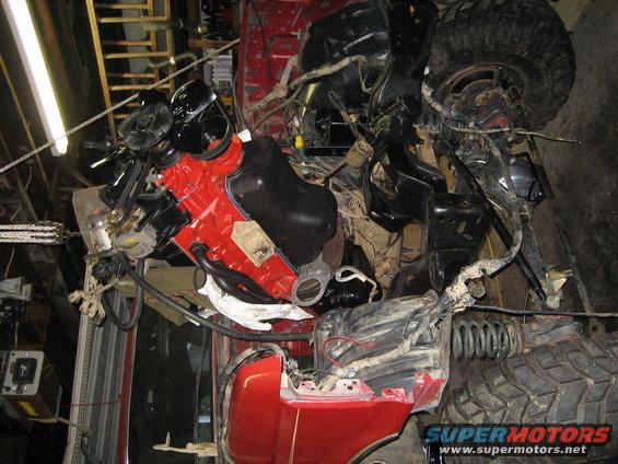 engine and suspension parts of a red vehicle, looks like it's being worked on