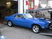 1969 Ford Mustang - A blue 1969 Ford Mustang is shown from a three-quarter front view, parked inside a garage with its hood open.