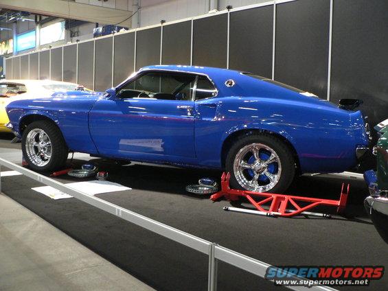 blue 1969 Ford Mustang on display with chrome wheels and spoiler