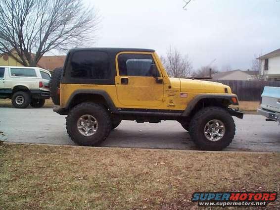 Yellow Jeep Wrangler side view with black hardtop and spare tire on rear