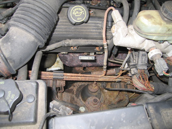 Engine bay of a 1991 Ford Crown Victoria LTD, showing rusty exhaust manifold and engine oil cap