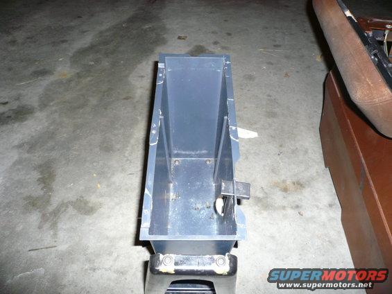 Plastic center console storage bin on a stand, with a brown seat in the background