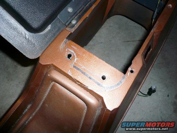 Close-up of a brown plastic car interior console piece with cut marks and holes