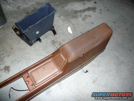Brown car center console and a black trash bin on a concrete floor
