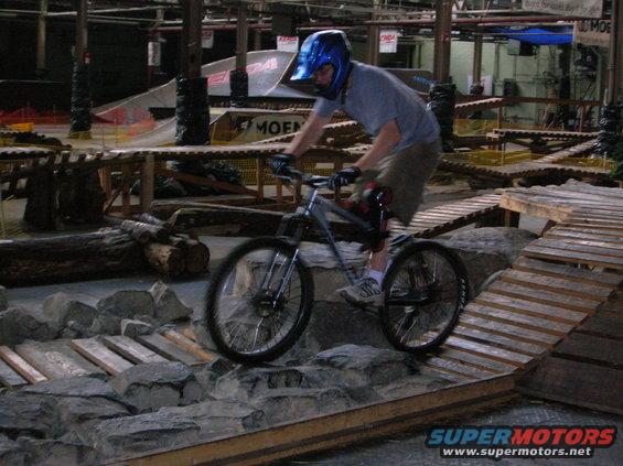 Person in helmet riding a mountain bike over rocks and wooden ramps