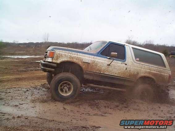 Mud-splattered SUV driving through mud, front quarter view
