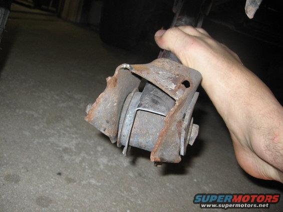 hand holding a rusty suspension component, possibly from a truck
