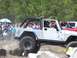 1989 Ford Bronco - A white Jeep Wrangler Rubicon navigates an obstacle course with spectators gathered.